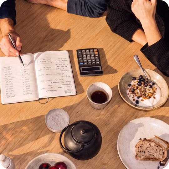 Anteckningsbok och miniräknare på ett bord när någon räknar på sina lån och sin budget